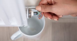 Frau dreht Hahn von Heizung auf zum entlüften