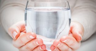 Hände die ein Glas mit klarem Wasser halten